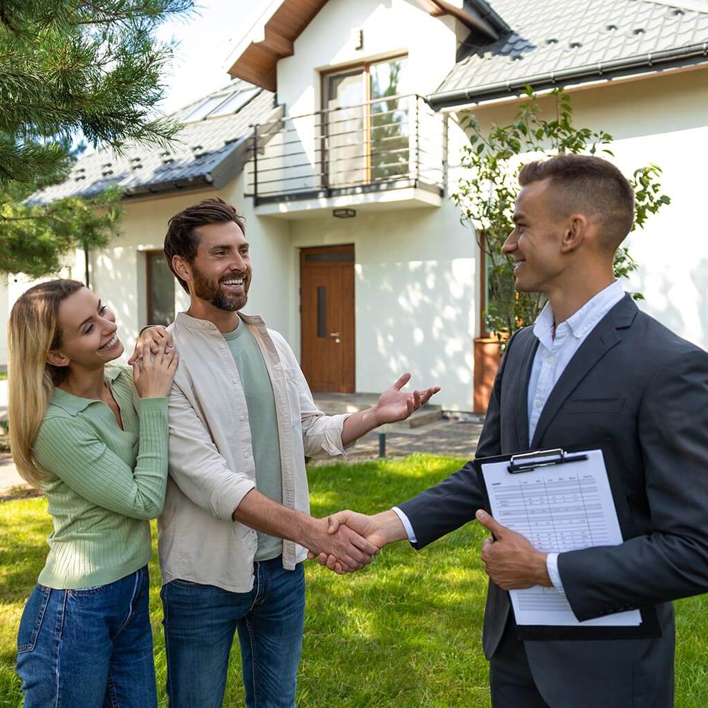 Couple shaking hands with real estate agent outside home Couple shaking hands with real estate agent outside home
