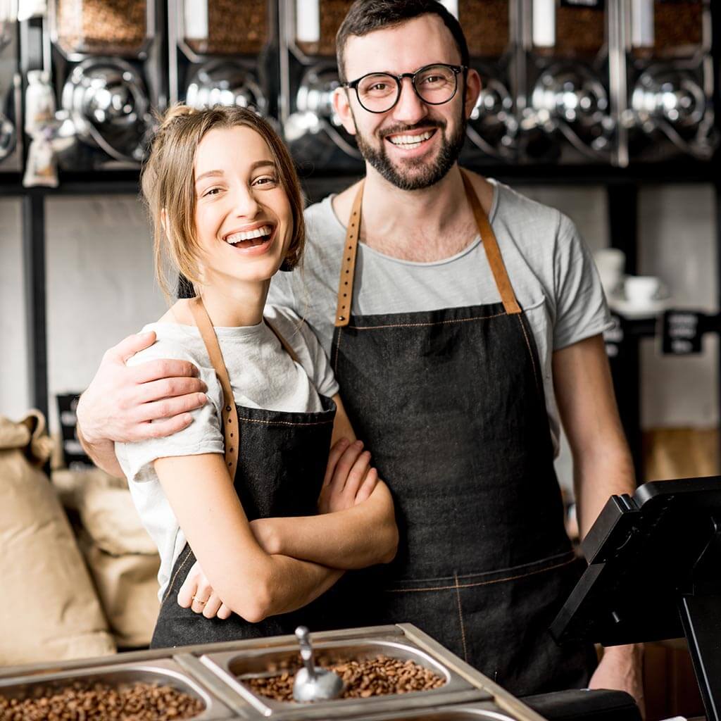 young couple of baristas standing together at the counter of the coffee store